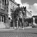 848106 Afbeelding van een jongetje dat op straat aan het steltlopen is, vermoedelijk in Amsterdam.